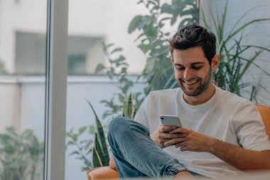 Genç adam cep telefonuyla evde.