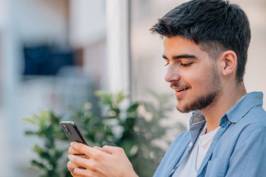 Genç adam caddede cep telefonuna bakıyor.