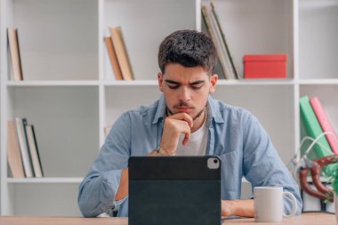young man at home or student with laptop with doubtful or pensive expression