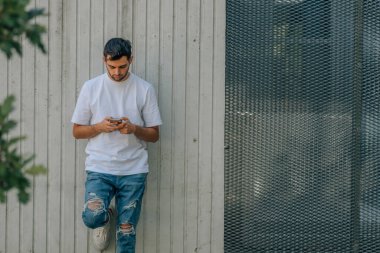 young man on the street wall looking at the mobile phone