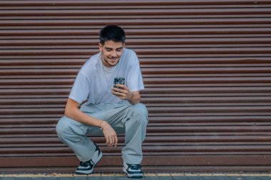 Şehirde cep telefonu olan genç ve şık bir adam.