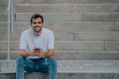 young man on the street stairs with mobile phone