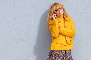 Dışarıda cep telefonuyla konuşan orta yaşlı bir kadın.