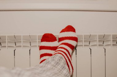 Çizgili çoraplı ayaklar evdeki ısıtma radyatöründe.