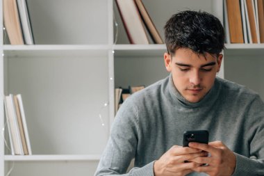 young man at home with mobile phone or smartphone