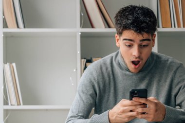 young man at home with mobile phone or smartphone