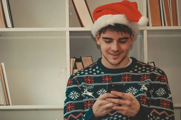 Щасливий Молодий Чоловік Вдома Мобільним Телефоном Капелюхом Санти Клауса Різдво — стокове фото