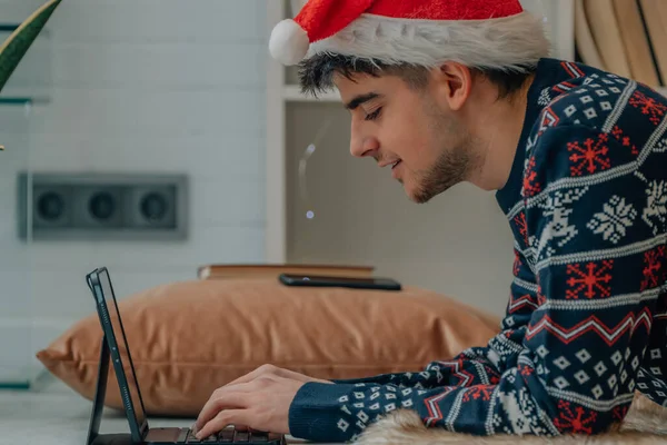 Młody Człowiek Boże Narodzenie Domu Wpisując Komputerze Lub Laptopie — Zdjęcie stockowe