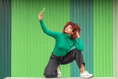 smiling african american latin girl with mobile phone making selfie or recording