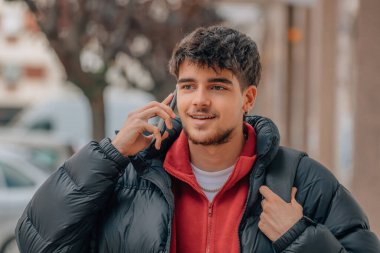 young student with mobile phone in the street in winter clothes