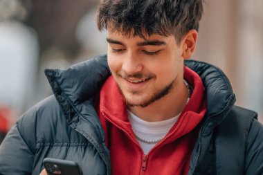 young man loocking mobile phone on street