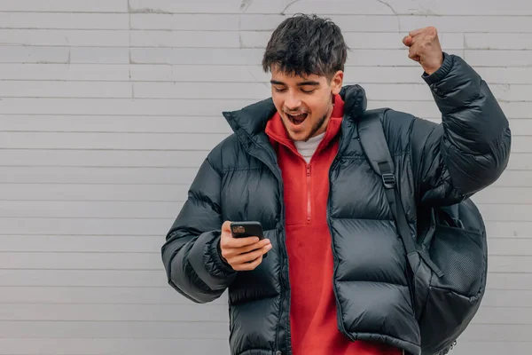 boy with phone in the street celebrating success
