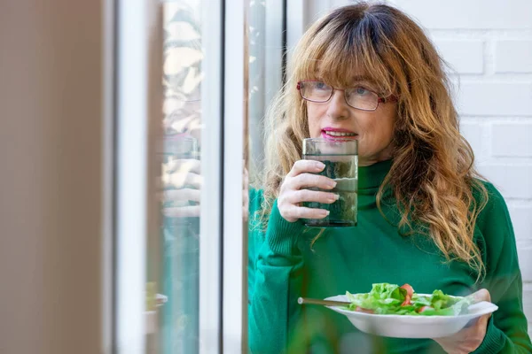 vegan woman at home with salad and glass of water