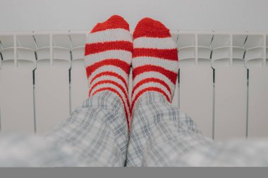 Çizgili çoraplı ayaklar evdeki ısıtma radyatöründe.