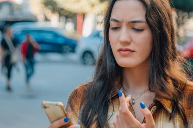 Sokakta cep telefonlu bir kadın anlaşmazlık ifadesi olan bir mesaj ya da spam dinliyor