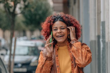 Modern kadın sokakta cep telefonuyla konuşuyor.