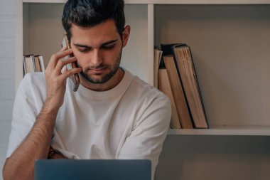 young man talking on the phone with laptop or computer