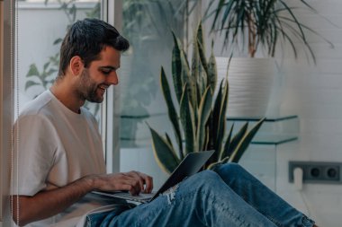 young man at home typing on computer