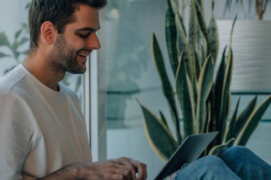 young man at home typing on computer