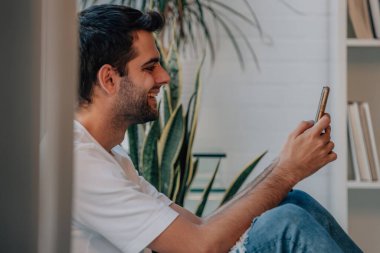 young man at home with mobile phone or device