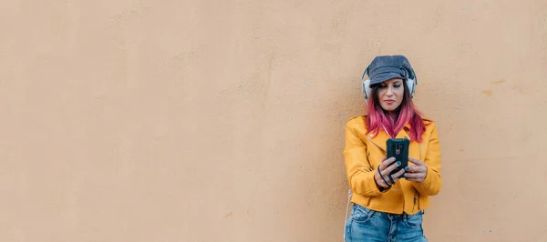 Mädchen Urbanen Stil Mit Handy Und Kopfhörern Isoliert Der Wand — Stockfoto