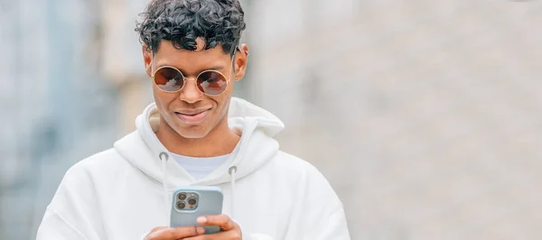Mladý Latinský Muž Slunečními Brýlemi Při Pohledu Mobilní Telefon — Stock fotografie