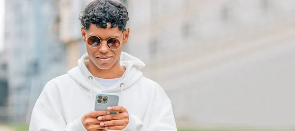 Młody Człowiek Okularach Przeciwsłonecznych Patrząc Telefon Komórkowy Ulicy — Zdjęcie stockowe