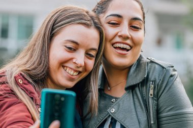 friends laughing in the street looking at the mobile phone