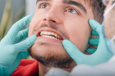 hands of dentist checking denture of patient in clinic