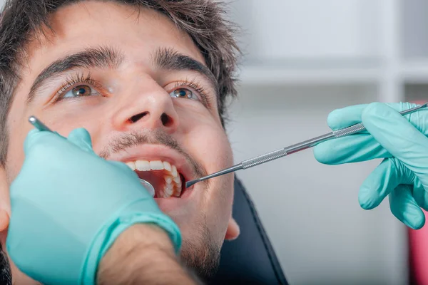 hands of the dentist with tools in the mouth of the patient