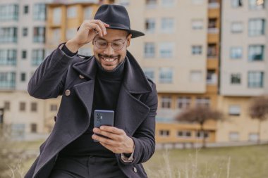 Sokakta cep telefonlu şık şapkalı bir adam.