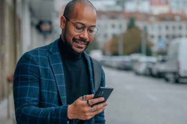Adam sokakta cep telefonuna bakıyor.