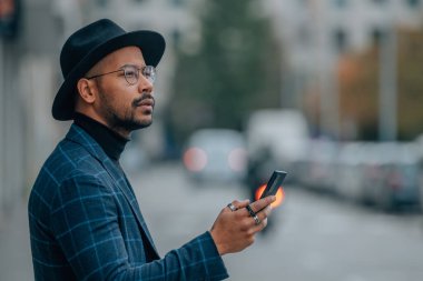 Şehir caddesinde cep telefonu olan Latin Amerikalı adam.