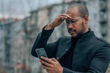 Sokaktaki adam cep telefonu ve şaşkınlık ifadesi ile