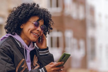 Caddedeki afro kız cep telefonuna bakıyor.