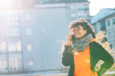 Şehirde cep telefonu olan kız gün batımında arka planda.