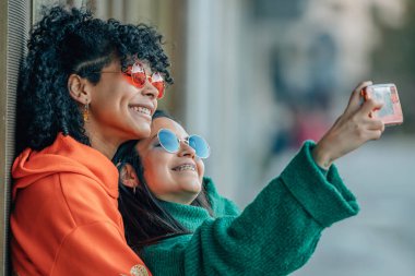 Telefonlu bir çift sokakta selfie çekiyor.