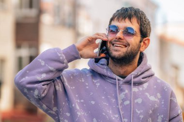 genç adam sokakta cep telefonu üzerinde konuşurken