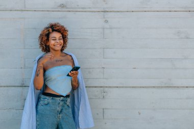 Siyah Latin Afrikalı Amerikalı kız cep telefonuyla sokakta.