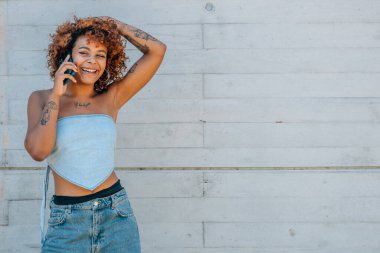 Siyah Latin Afrikalı Amerikalı kız sokakta cep telefonuyla konuşuyor.