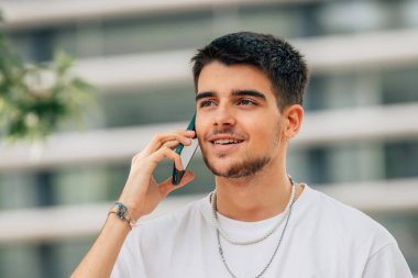 genç adam sokakta cep telefonu üzerinde konuşurken