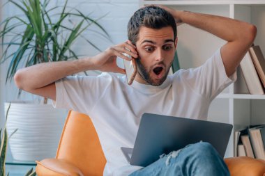 Evdeki adam şaşırmış bir ifadeyle cep telefonuyla konuşuyor.