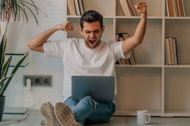 Evdeki genç adam sevinçten dizüstü bilgisayarla kutlama yapıyordu.