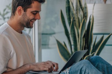 Evde dizüstü bilgisayarı olan genç adam.