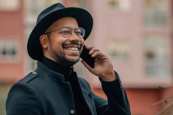 smiling latin man talking on mobile phone in the street