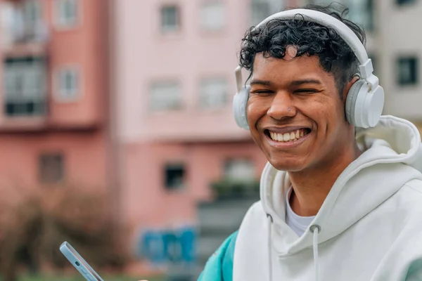年轻的拉丁裔男子 手持手机和耳机 — 图库照片