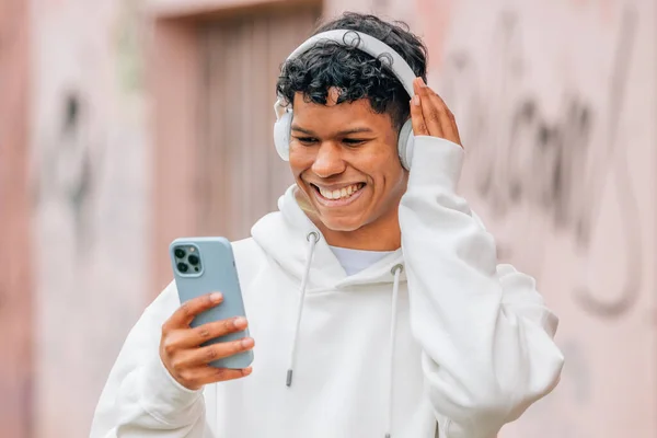 携帯電話やヘッドフォンを持ったラテン系アメリカ人の若者が音楽を聞き — ストック写真