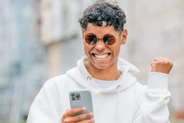 Mladý Muž Slunečních Brýlích Při Pohledu Mobilní Telefon Ulici — Stock fotografie