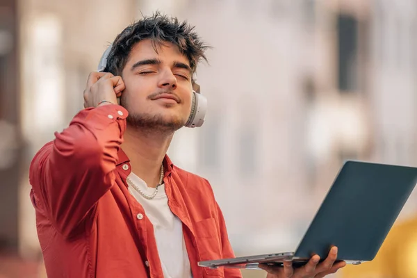 Νεαρός Άνδρας Ακουστικά Και Laptop Ακούγοντας Μουσική Στο Ύπαιθρο — Φωτογραφία Αρχείου