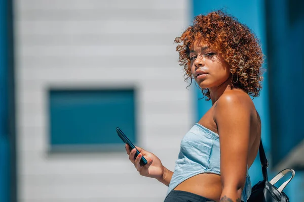 街中に携帯電話を持ったラテン系の黒人の女の子が — ストック写真